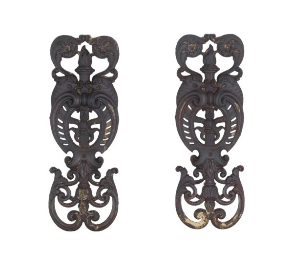 Pair of ornate cast iron balustrades with figural and torch details, shown side by side.