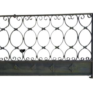 Wrought iron fence section with looping scrollwork above a cast iron base panel with foliage details.