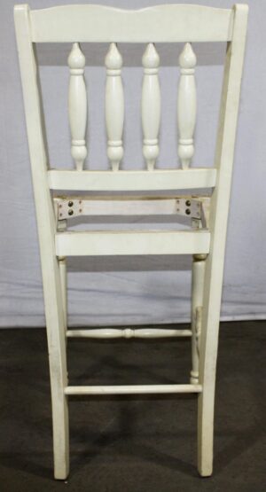 Back view of a white wood chair frame with turned spindles and no seat.