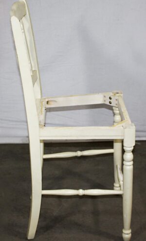 Side view of a white wood chair frame with no seat, showing the tall back, arm supports, and turned front leg.