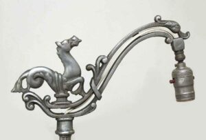 Antique floor lamp with a horse motif and curved arm, shown in close-up with the lamp socket and decorative metalwork visible.