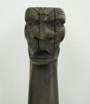 Close-up of a dark wood tone pine snake carving showing the carved face and long neck.
