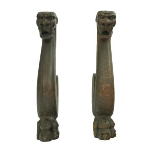 Pair of pine wood snake carvings shown upright as a matching pair, each with a carved head at the top and a paw-like base, in a dark wood tone with visible age wear.