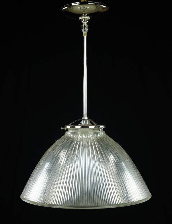 Pendant light with a clear holophane glass shade and polished nickel pole.