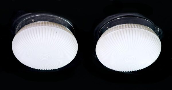Pair of mid century flush mount lights with white ribbed glass shades and polished nickel mounts.