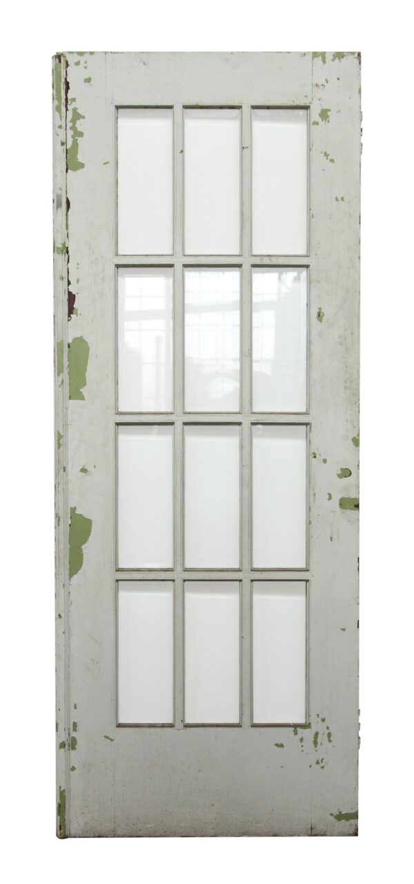 White wood French door with 12 beveled glass lites shown front view, featuring worn painted edges and a tall rectangular frame.