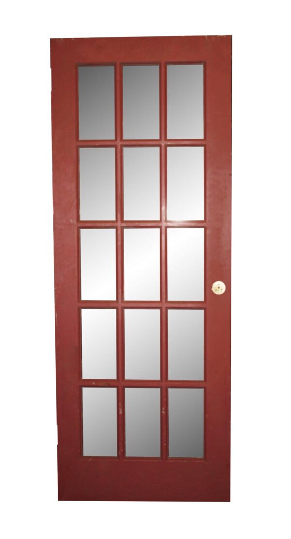 Painted wooden French door with 15 glass lites, shown with the red side and a round latch hole on the right edge.