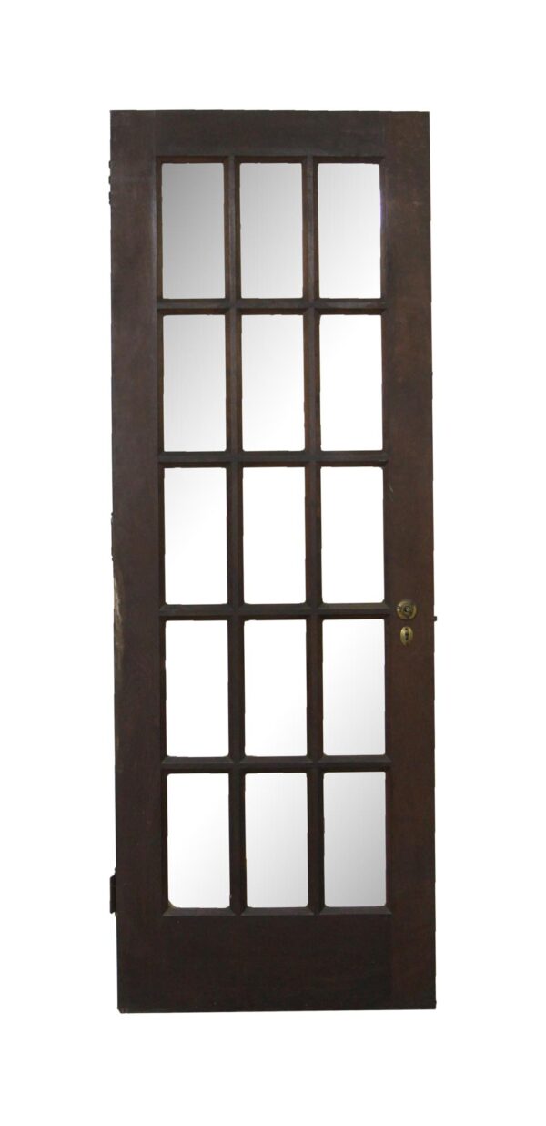 Dark wood tone French door with 15 glass panes and a hole in one pane, shown with a metal lock set on the right side.