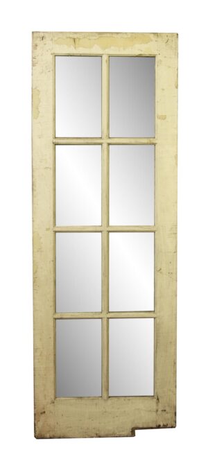 Antique wooden French door with eight glass panes and a weathered painted finish.
