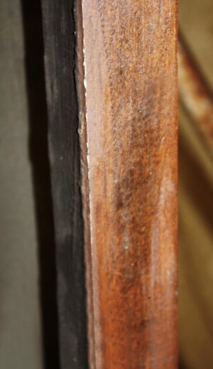 Close-up of a dark wood tone door edge showing the frame and narrow glass joint.