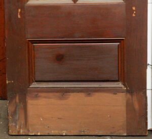 Dark wood door with a single raised panel, shown close up.