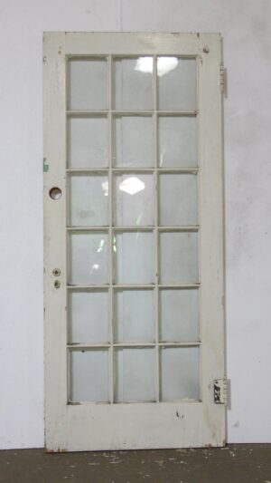 Vintage white-painted wooden door with 15 glass panes and visible wear from age and use.