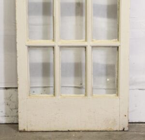 White 18-lite French passage door with six visible glass panes in a weathered painted wood frame.