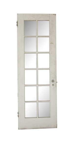 Vintage white wooden French door with 12 glass panes and original hardware visible on the edge.