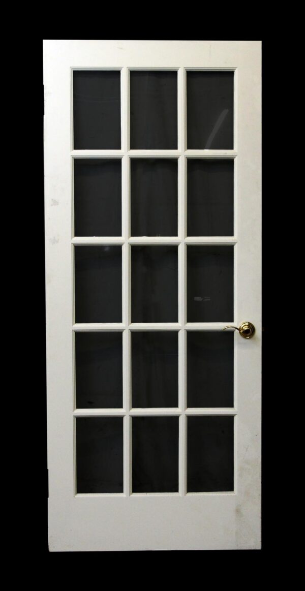 White wood French door with 15 glass panes and a round brass knob.
