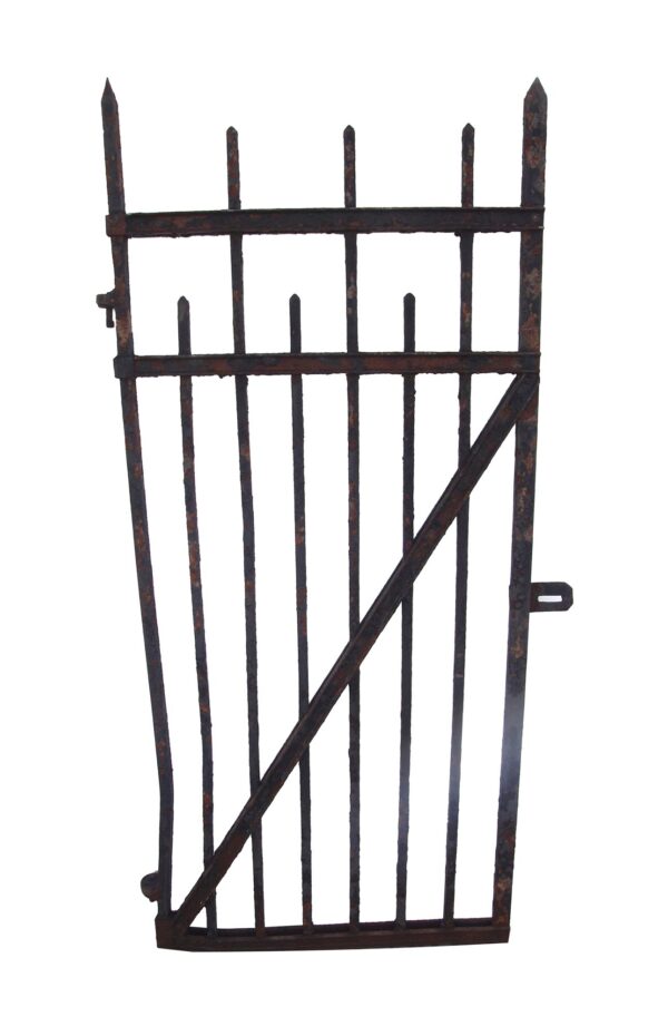 Narrow cast iron walkway gate with vertical bars, pointed finials, and a diagonal brace, shown as a single gate panel with a rusted finish.