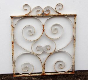 Antique small wrought iron gate with white paint and rusted scrollwork, shown front on.