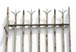 Distressed green wrought iron gate with split finials and peeling paint, shown in a front view.
