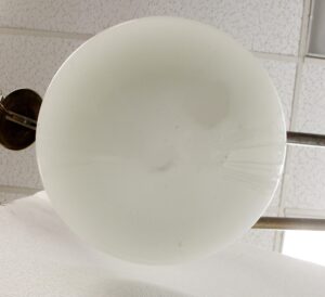 White milk glass schoolhouse light globe shown from below, with a brass chain fitter visible at the side.