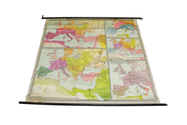 German school wall map on paper with multicolored historical maps and black hanging rods at the top and bottom, shown with visible age wear and stains.