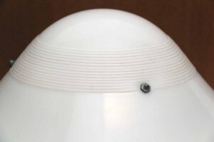 Close-up of a white glass rounded shade with a ribbed band and visible mounting screws near the rim.