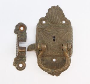 Antique bronze Art Nouveau ice box latch shown with the latch body and matching strike plate, featuring ornate scrollwork and a right-swing catch opening.