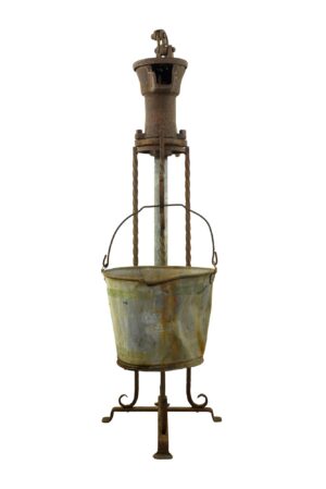 Antique cast iron hand water pump with attached steel bucket, shown front view with heavy rust and a visible handle.