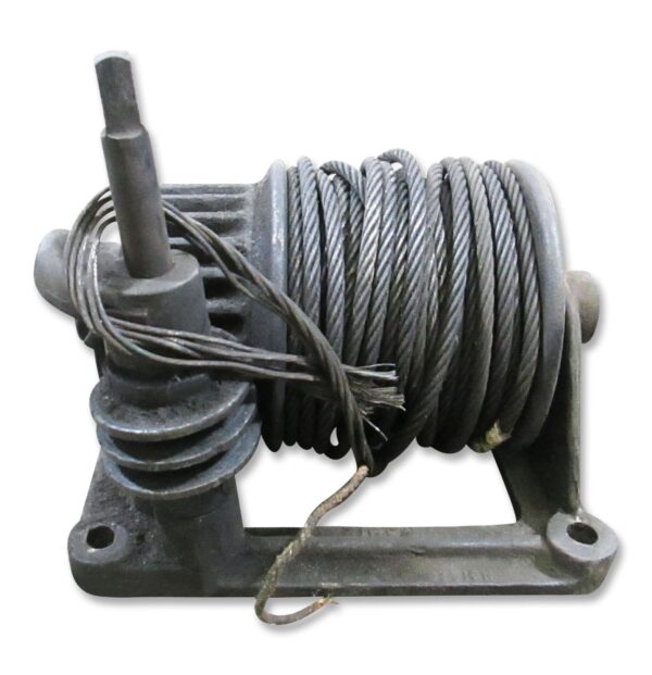Industrial cast iron pulley with coiled wire rope and a mounting base shown in a close-up view.