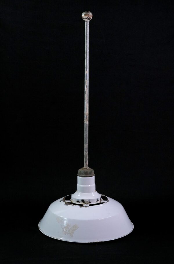 Industrial pendant light with a white enameled steel shade, long steel pole, and visible chipping and rust around the top opening and rim.