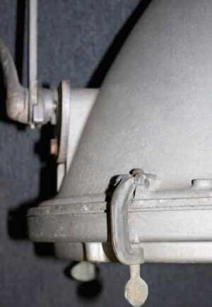 Close-up of an industrial spotlight with an aluminum housing and visible clamp hardware attached to the side.