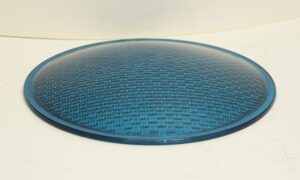 A convex blue glass panel with a textured surface and rounded edge, shown from above as a single circular piece.