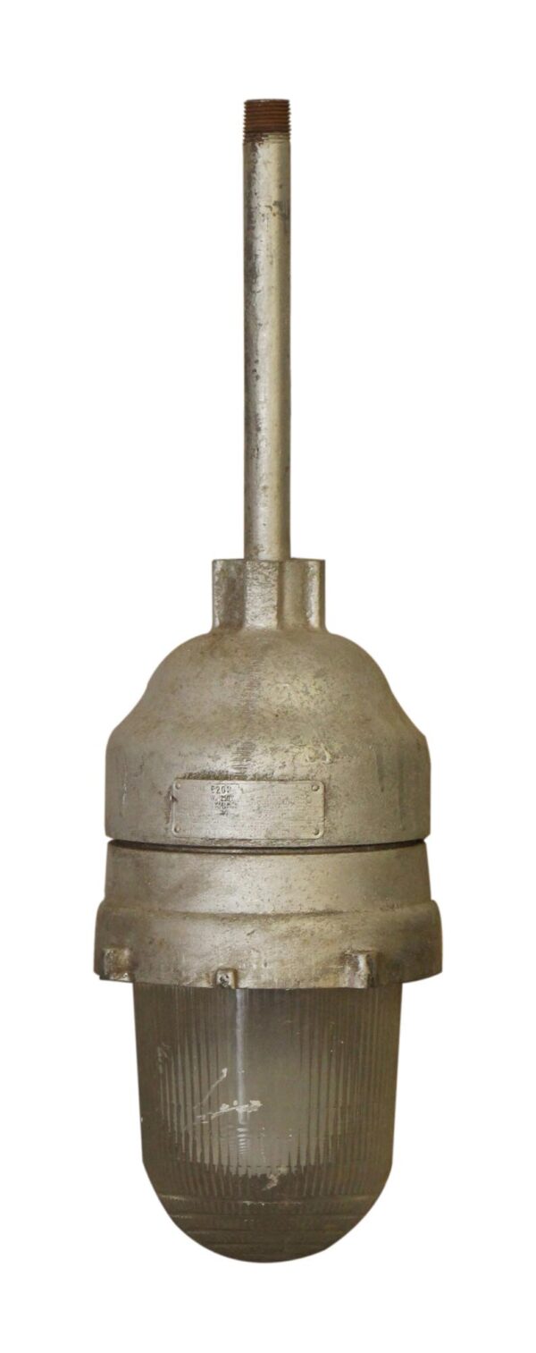 Industrial pendant light with a gray metal housing and ribbed glass lens, shown with a long threaded stem.