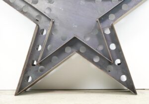 Steel star-shaped light frame with perforated metal panels and visible rust along the edges, shown close up as the front-facing frame only with no bulbs.