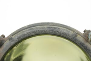 Close-up of a steel and glass flood light with embossed Pyle-National Company lettering around the rim and a clear lens.