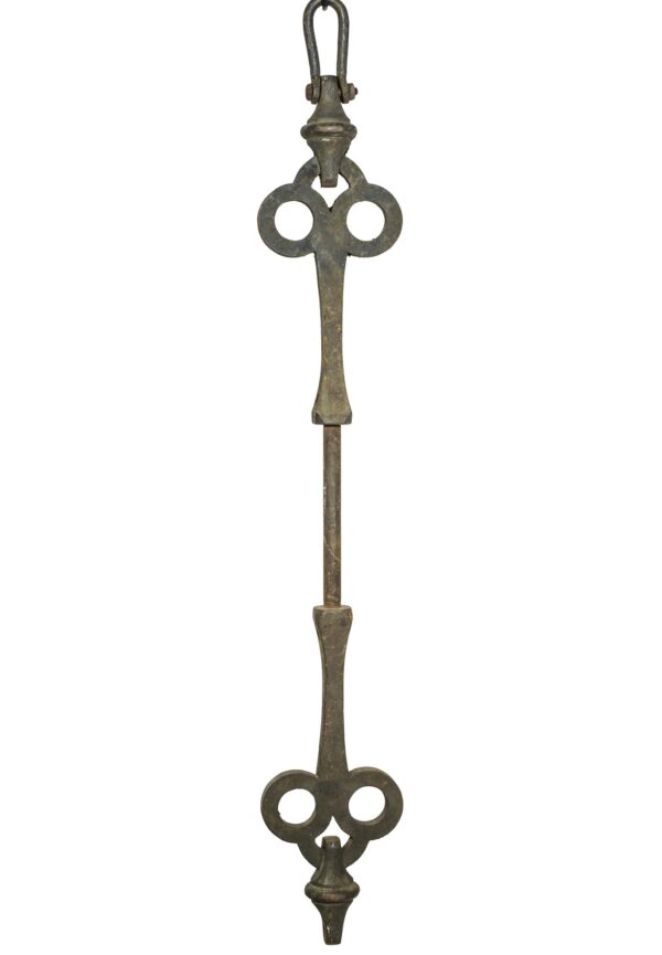 Ornate cast iron support with connecting loops at both ends and a narrow central stem, shown vertically with some rust and an aged black finish.