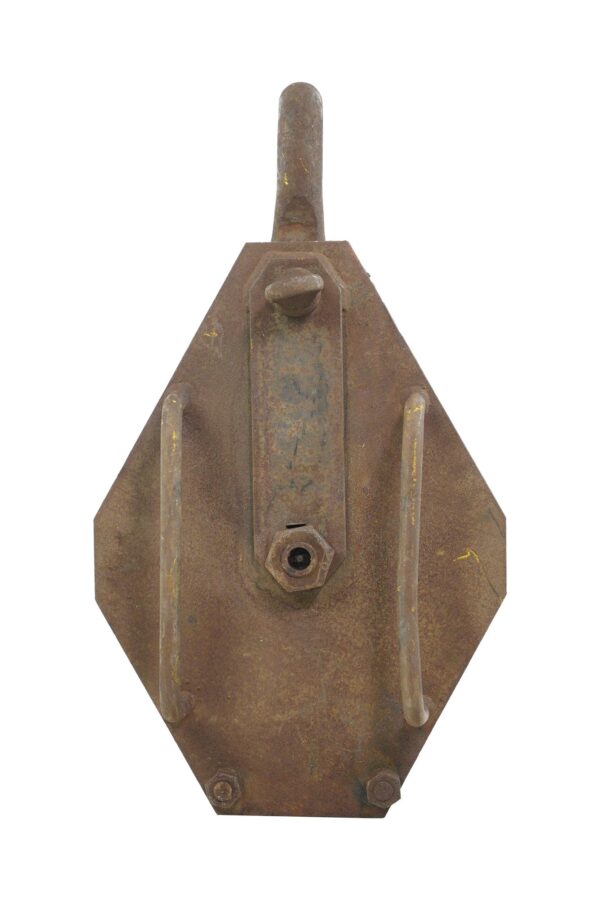 Vintage steel loop pulley with two wheels, showing the rusted side of the mechanism and mounting hardware.