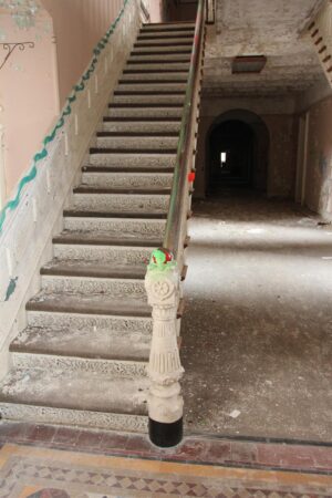 Victorian cast iron staircase with a right-side railing, shown in a worn interior view.
