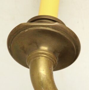 Close-up of an antique bronze wall sconce showing the round canopy and curved arm.