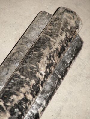 Close-up of a black reclaimed wooden banister showing the wide base and thinner handrail on top.