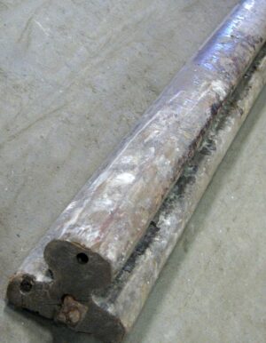 Close-up of a reclaimed wooden banister handrail with a drilled end and visible wear.