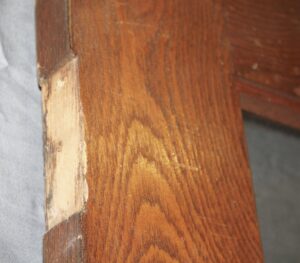 Close-up of an oak French door showing a damaged edge and the frame around one of the 15 panes.