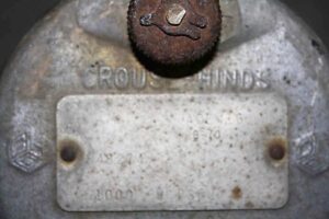 Close-up of an industrial spotlight housing with a rusted adjustment knob and a rectangular identification plate on the back.