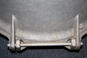 Close-up of an industrial aluminum spotlight housing with a mounting bracket and horizontal pin visible at the bottom.