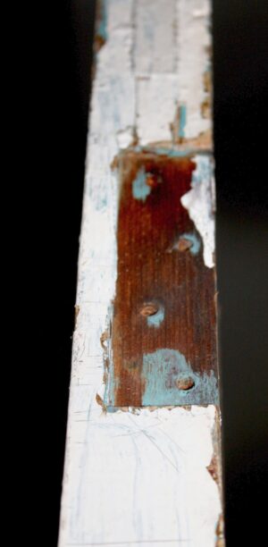 Antique white entry door shown in close-up, with a vertical upper glass opening missing the pane and a worn lower wood panel.