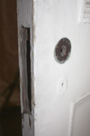 Close-up of a white wooden passage door showing the edge latch recess and a round hardware hole.