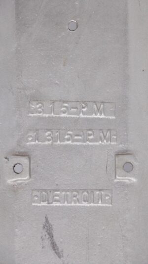 Back of a vintage 15-inch aluminum door push plate with mounting holes and embossed Detroit markings, shown in close-up with visible surface wear.