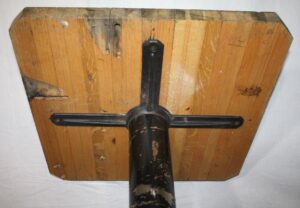 Underside view of a bistro table with a butcher block top and cast iron base, showing the iron mounting bracket and central pedestal attachment.
