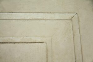Close-up of a white wooden one-panel door showing the upper corner of the panel and trim detail.