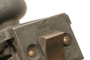 Close-up of an Art Deco cast bronze door lock set showing the attached lock box and part of a doorknob and back plate.