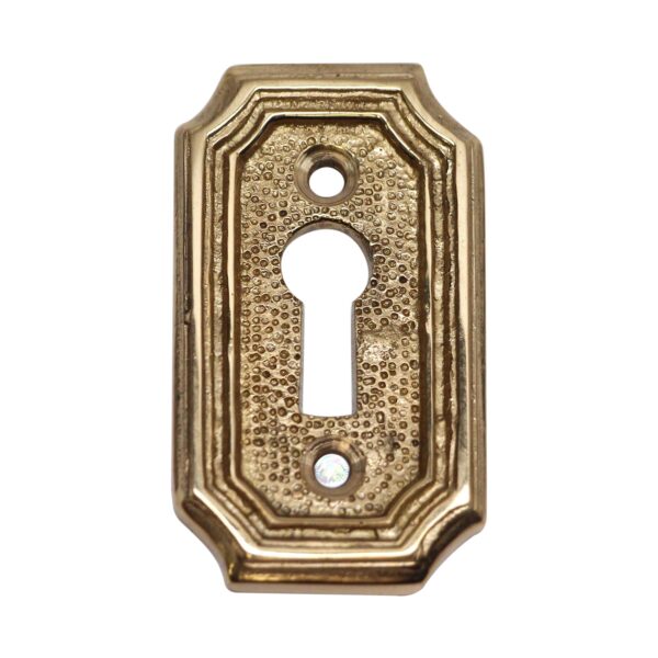 Solid brass keyhole cover with an arched edged shape and textured center, shown with keyhole opening and two screw holes.